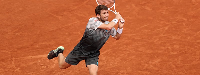 Cam Norrie mid swing on clay court