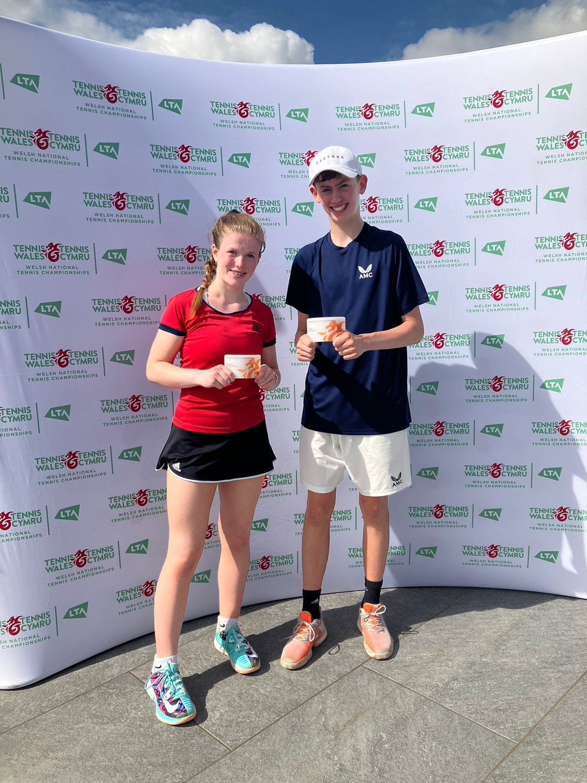 Two young tennis champions holding their awards