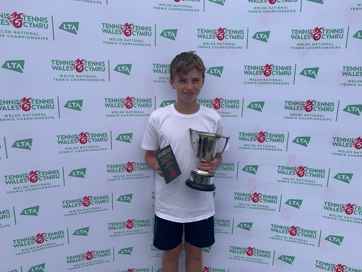 Archie posing with his trophy infront of tennis wales backdrop