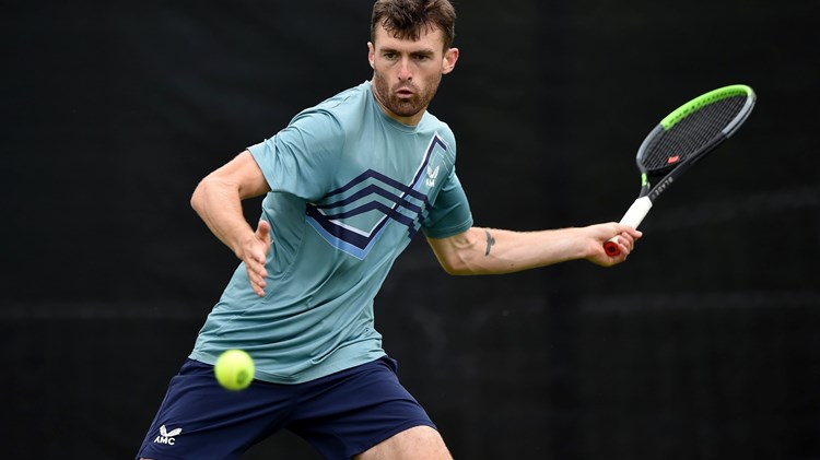 Giles Hussey swinging a tennis racket