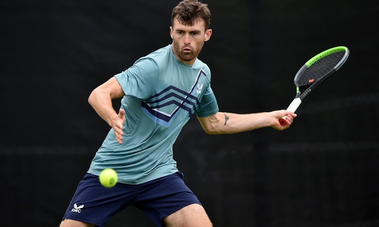 Giles Hussey swinging a tennis racket