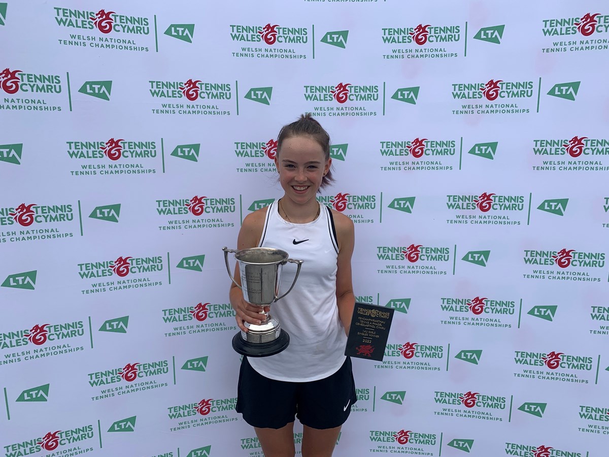 tennis under14 girls champion posing with her trophy