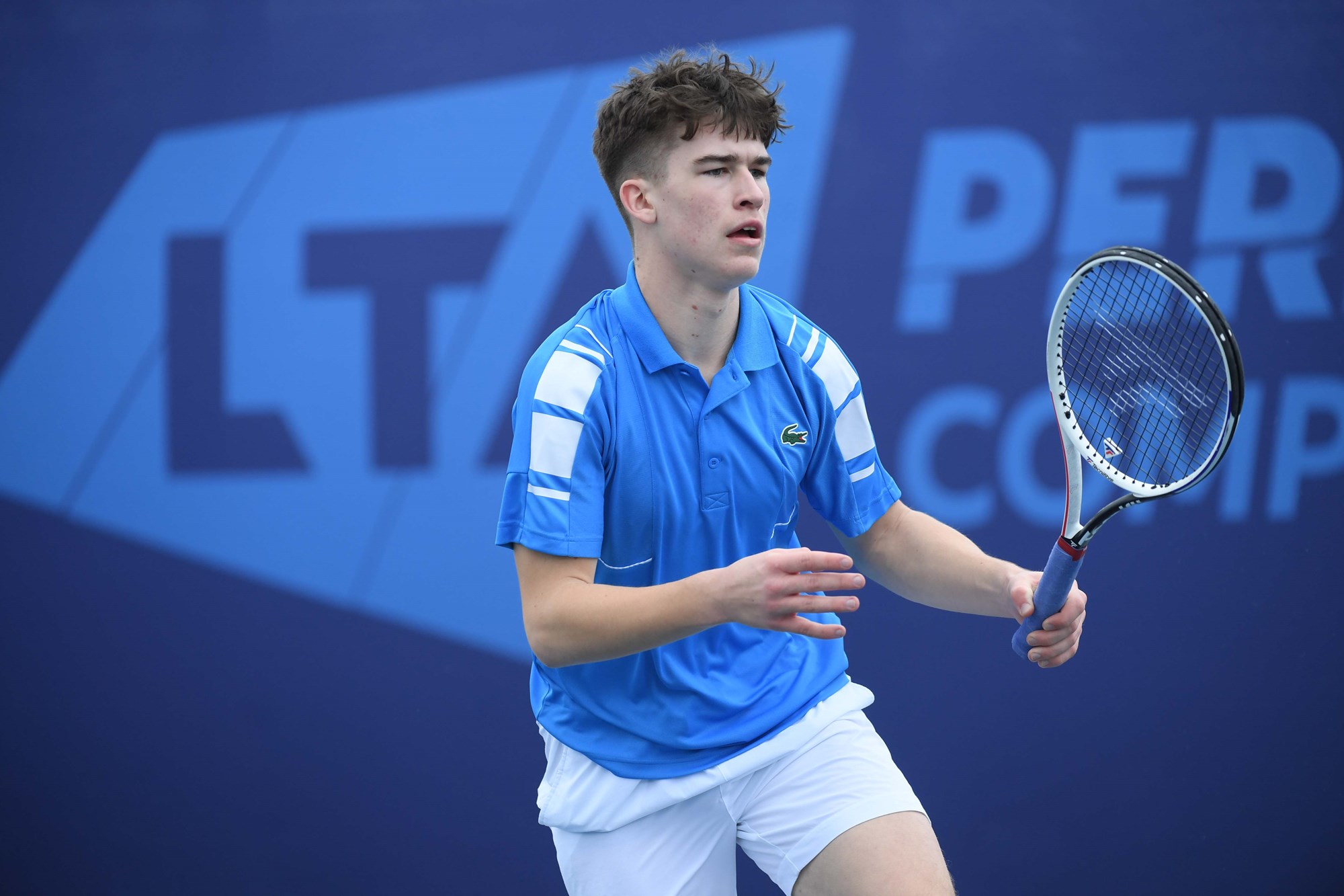 Male wearing a blue shirt with a racket in his hand 