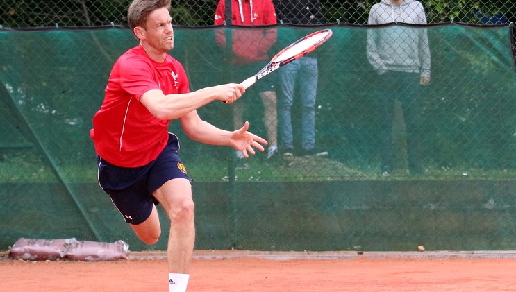Man returning tennis shot in the middle of a game
