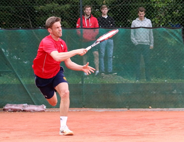 Man returning tennis shot in the middle of a game