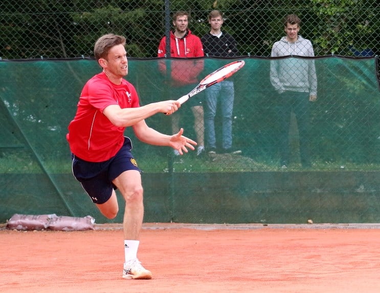 Man returning tennis shot in the middle of a game