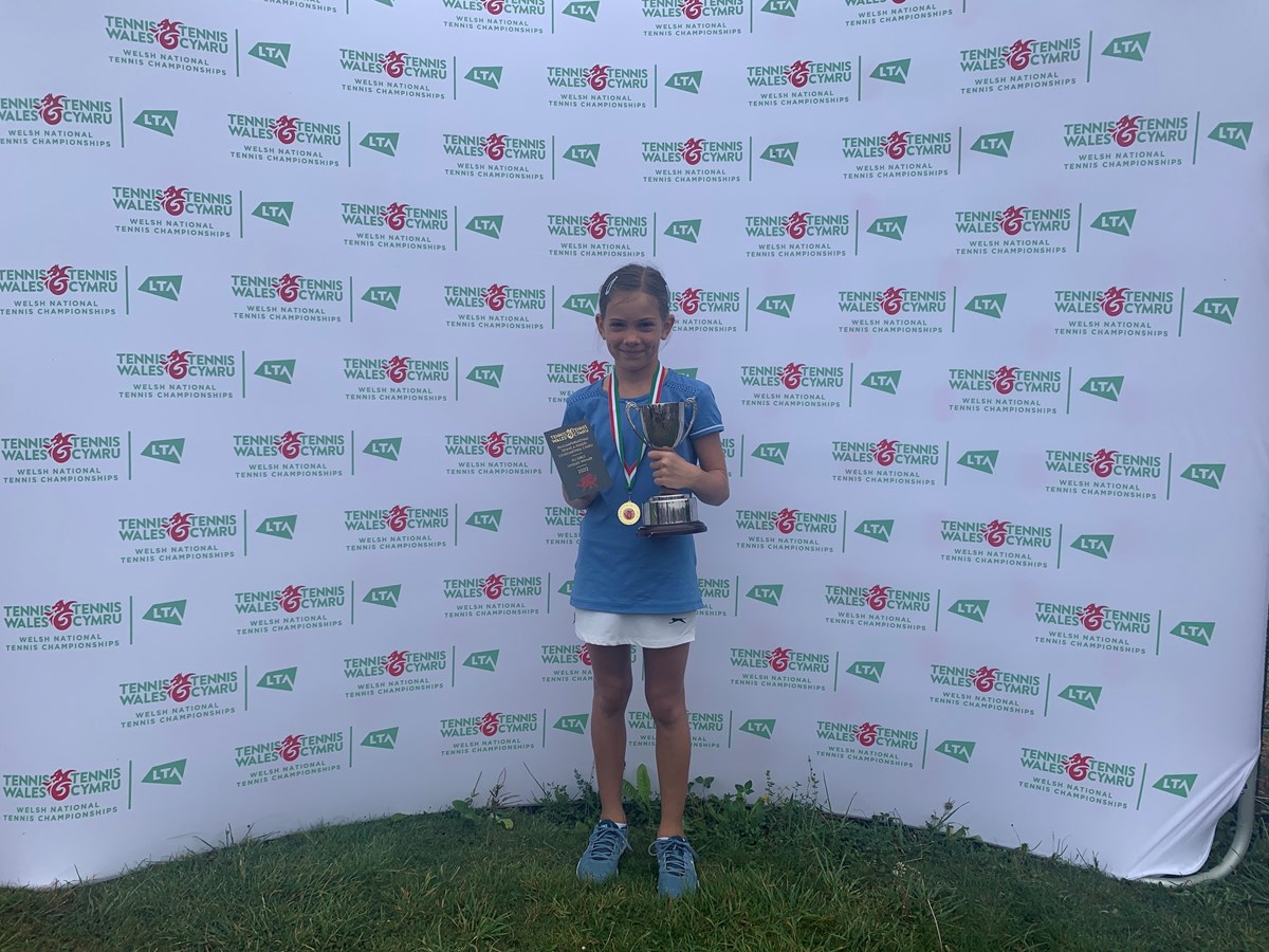 Zara posing with her trophy infront of tennis wales backdrop