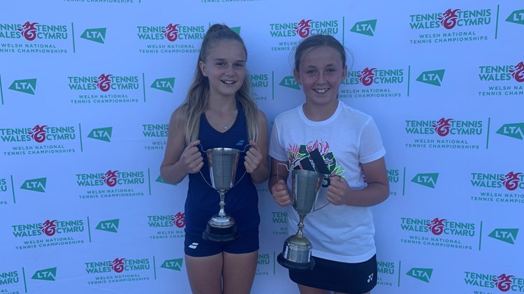 Two young tennis champions posing with their trophies