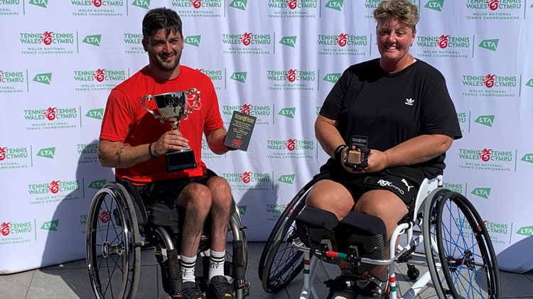 Two wheelchair tennis champions holing their trophies