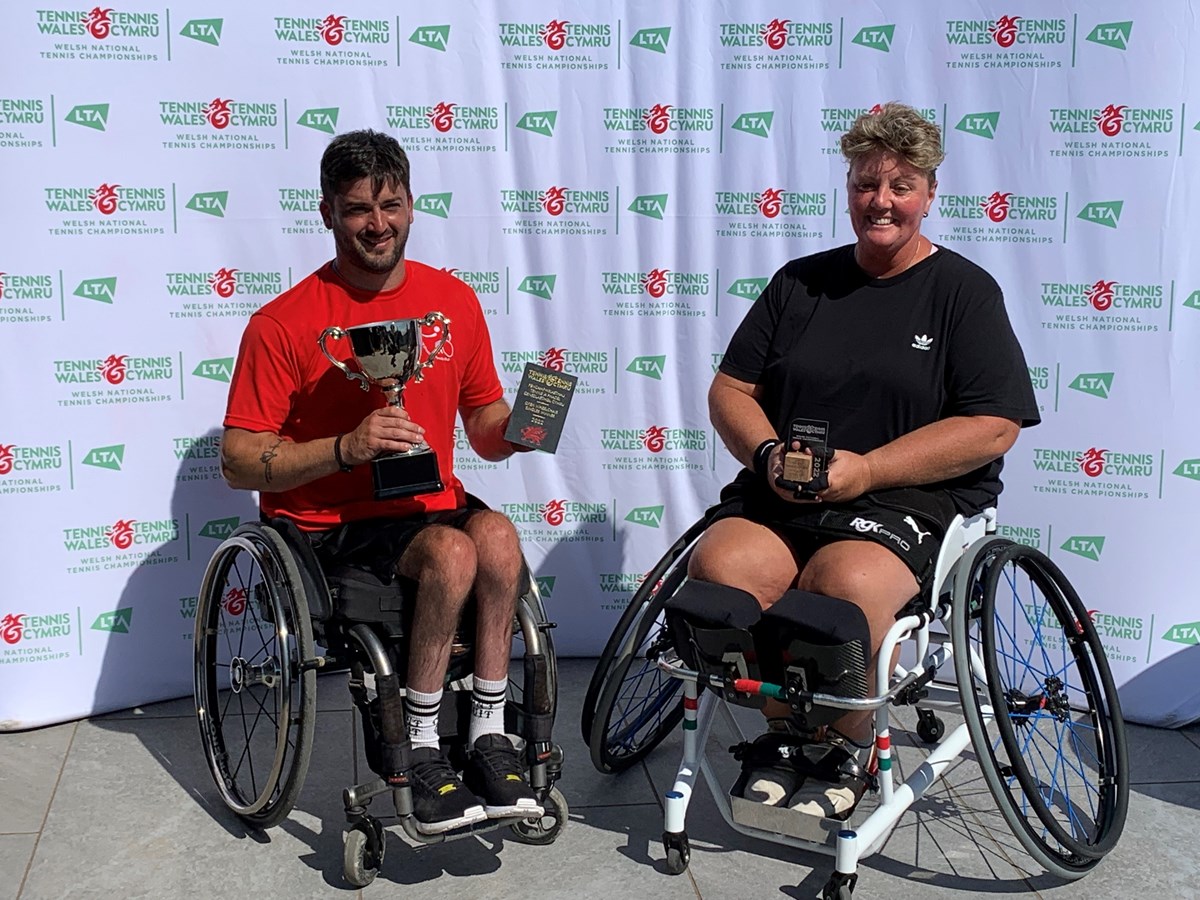 Two wheelchair tennis champions holing their trophies