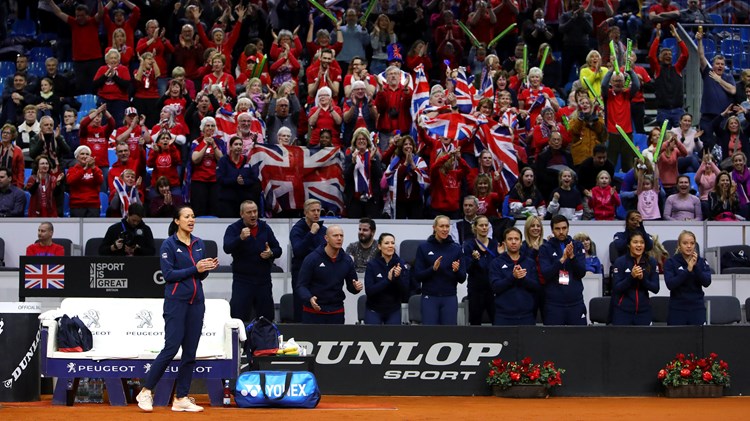 Tennis player clapping with fans in background