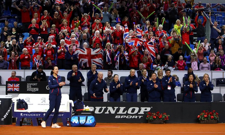 Tennis player clapping with fans in background