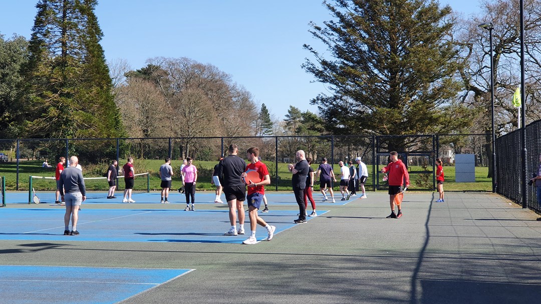 Large tennis lesson taking part on outdoor tennis court