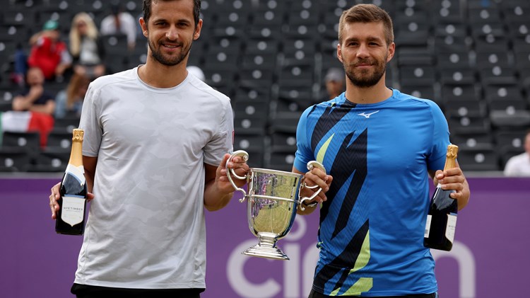 Two male players with a trophy and a champagne bottle