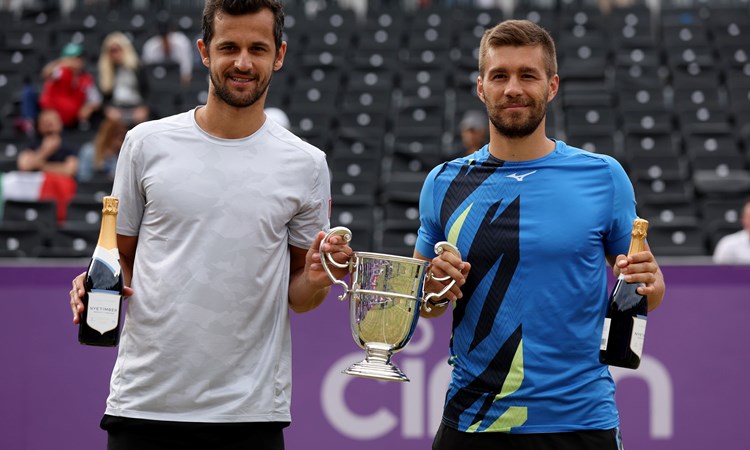 Two male players with a trophy and a champagne bottle