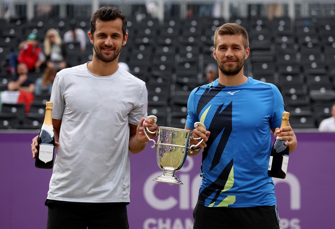 Two male players with a trophy and a champagne bottle