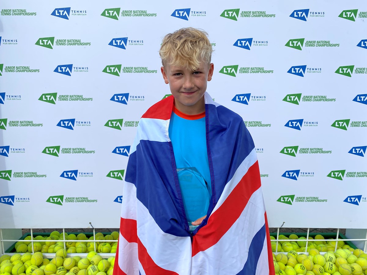 Oliver posing with the flag infront of the LTA backdrop
