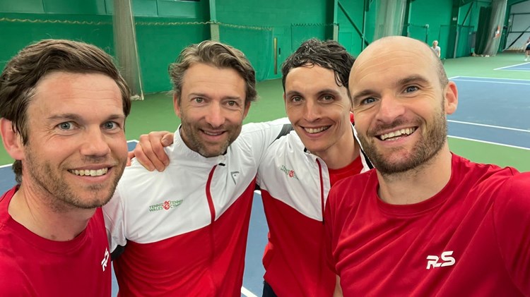 4 men posing infront of the camera in an indoor court