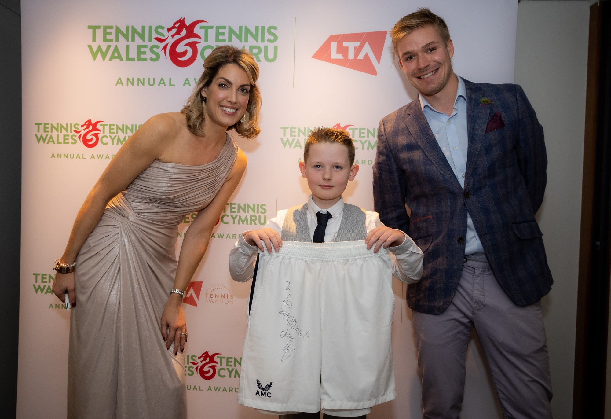 Child standing with signed shorts at an award ceremony 