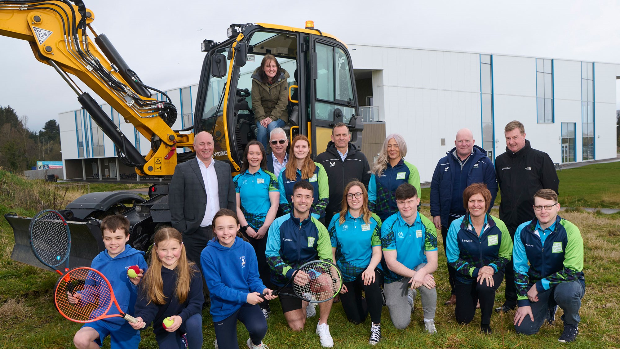 A group of people in front a construction machine