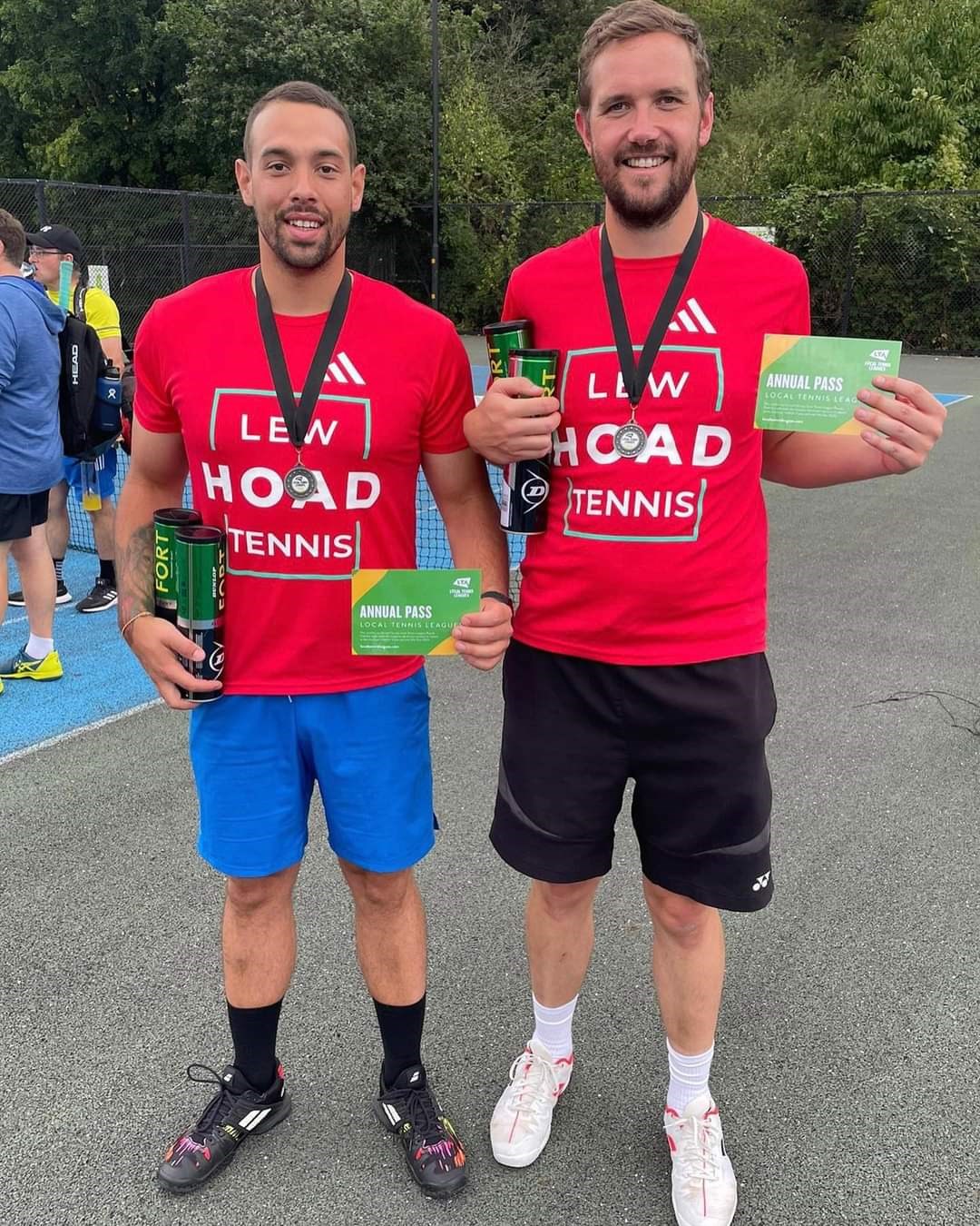 Two tennis players posing with their trophies after a tournament 