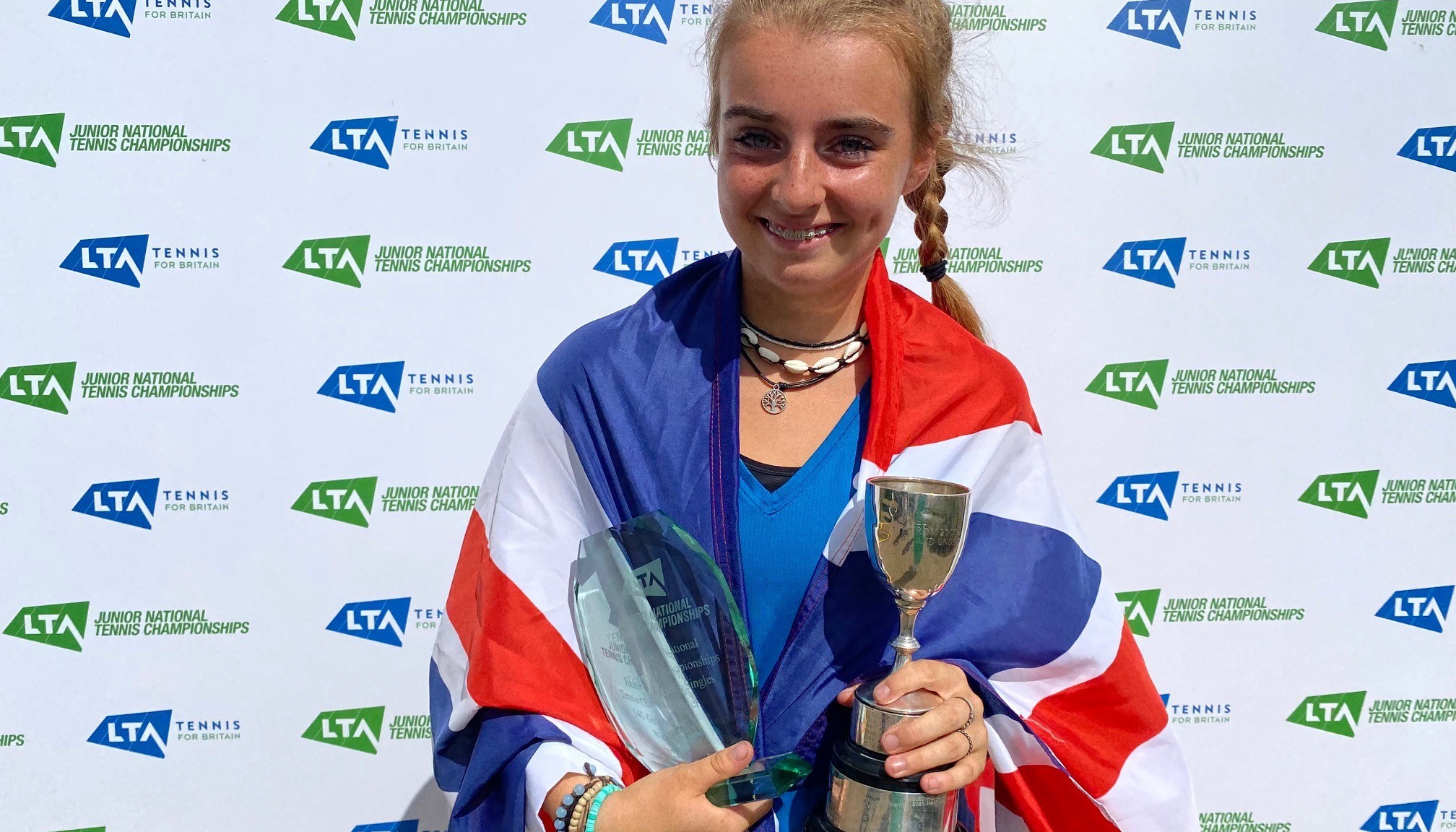 Female holding a trophy wrapped around in a flag