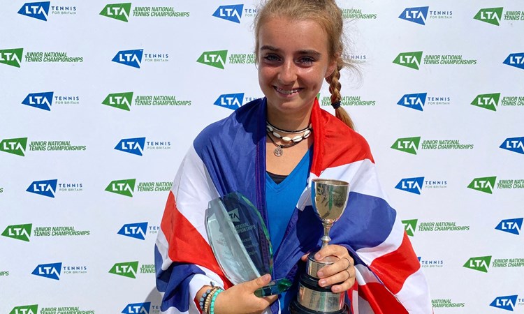 Female holding a trophy wrapped around in a flag