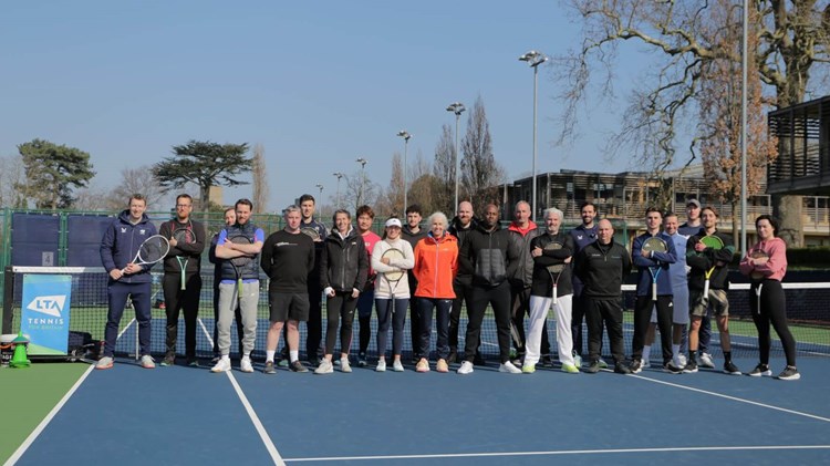 A group of people holding rackets on a tennis court