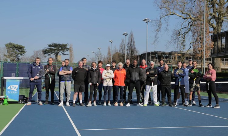A group of people holding rackets on a tennis court