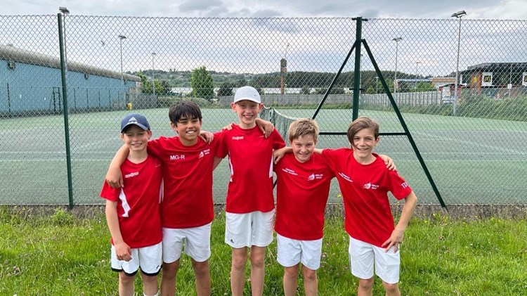 Young children posing after a youth tennis lesson on an outside court