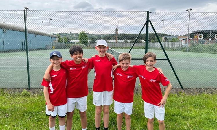 Young children posing after a youth tennis lesson on an outside court
