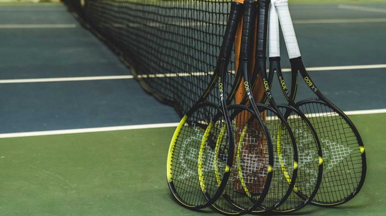 Bunch of tennis rackets resting on a pole