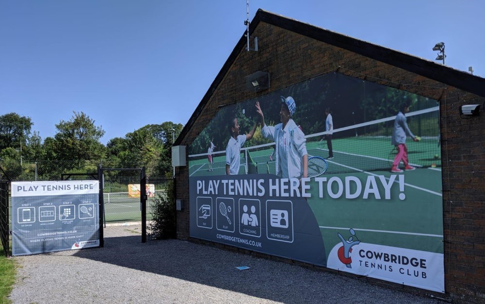 Play tennis here today sign on the wall of a venue 