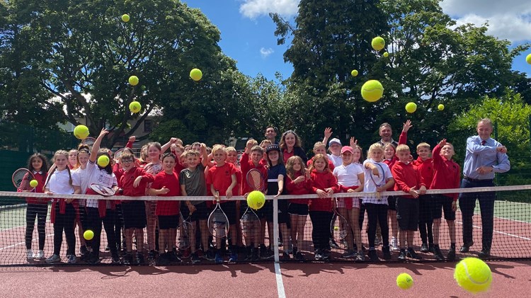 Group of children behind a net during a youth tennis lesson