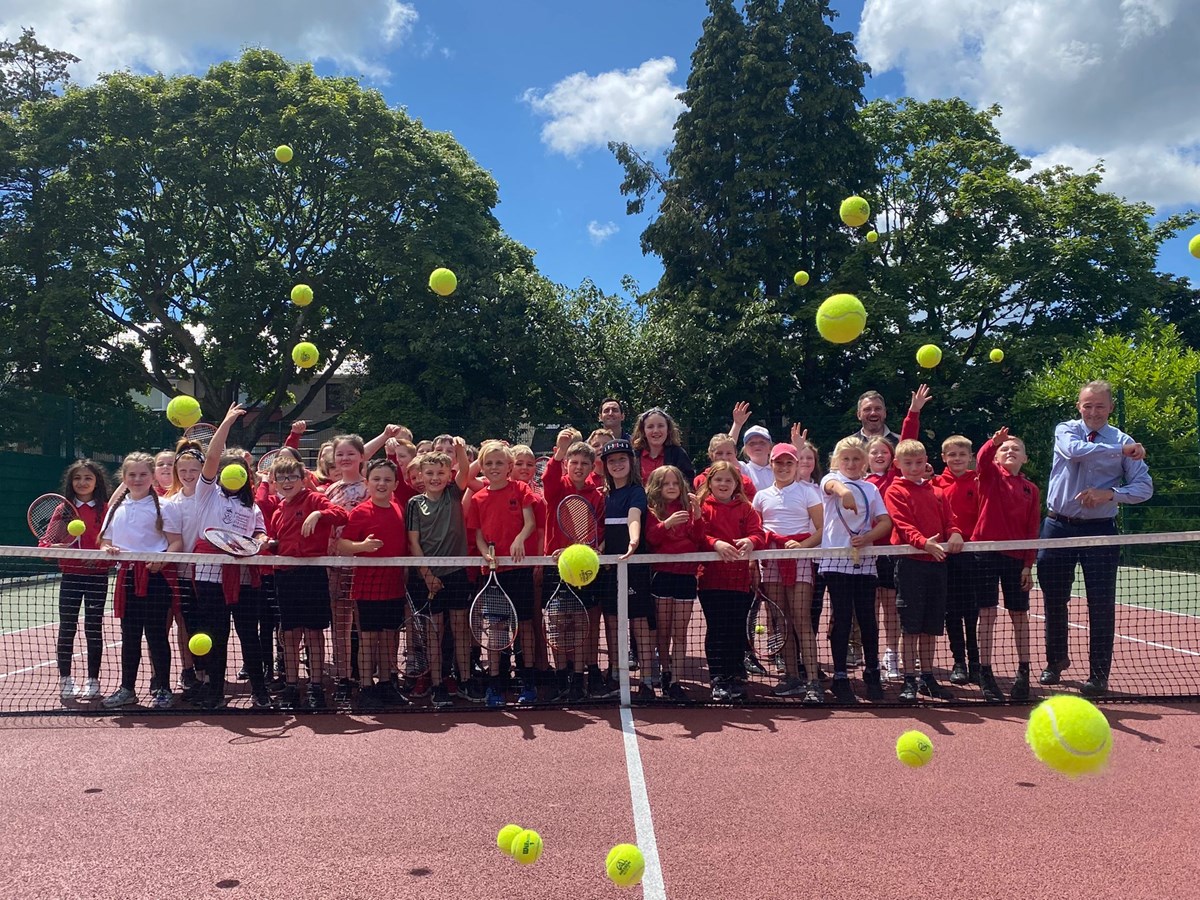 Group of children behind a net during a youth tennis lesson