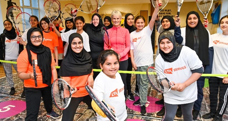nalette tucker and judy murray standing between a group of kids wearing lta serves tops all holding rackets up 