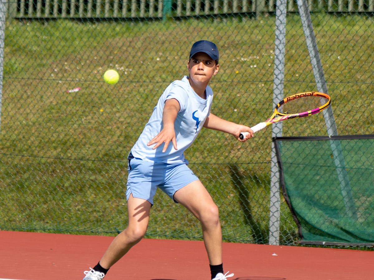 Youth playing returning a shot mid game concentrating on the ball