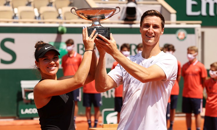 Female and male tennis players holding a trophy