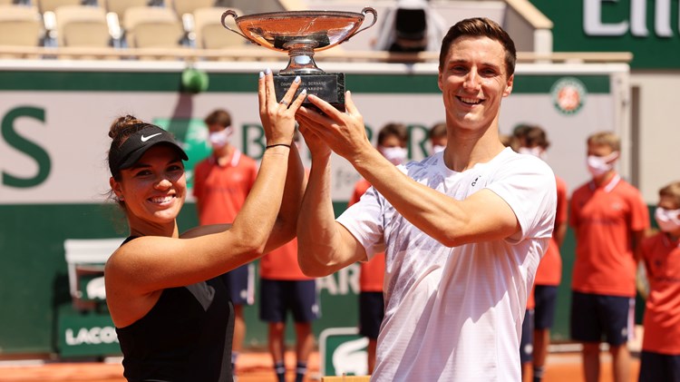 Female and male tennis players holding a trophy