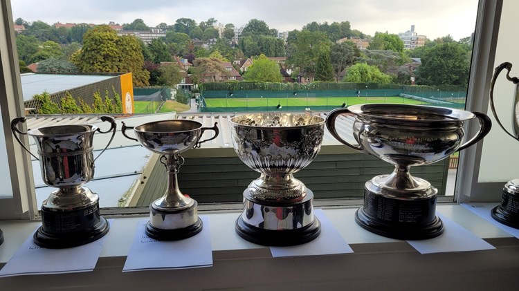 Championship trophies with a tennis court view in the background