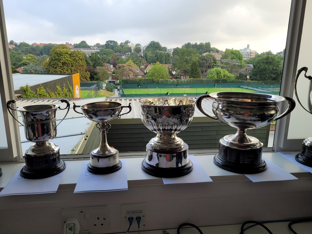 Championship trophies with a tennis court view in the background