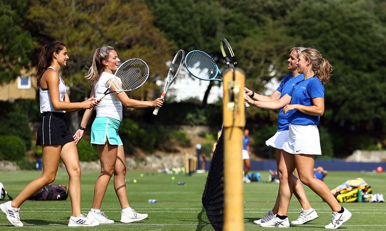 Four female tennis players cheering each other