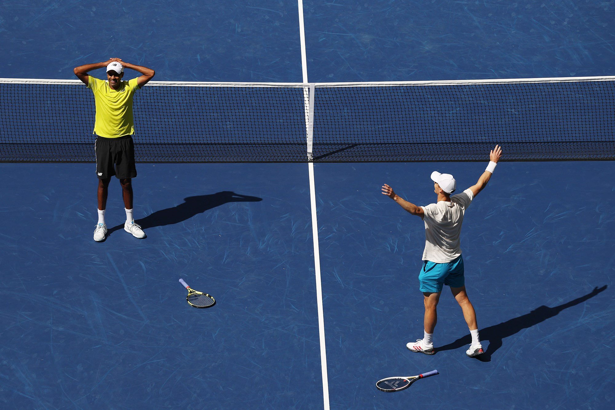 Two male players with rackets on the ground