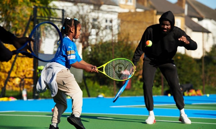 A young girl hitting a ball with a racket at a Free Park Tennis session