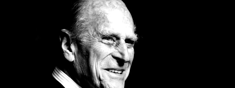 A black and white headshot of Prince Philip smiling