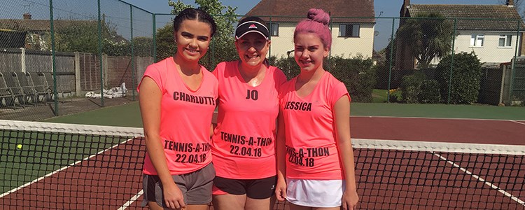 Jo Stehle standing on court with her two daughters wearing pink tennis-a-thon t-shirts