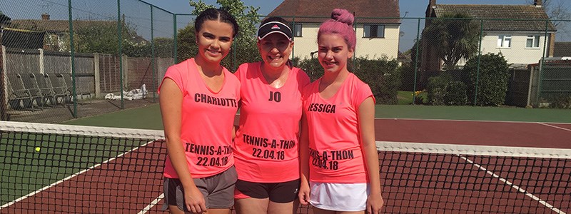 Jo Stehle standing on court with her two daughters wearing pink tennis-a-thon t-shirts