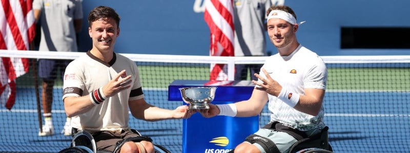 hewett and reid holding trophy in one hand and other hand holding up four fingers with us open logo at the back