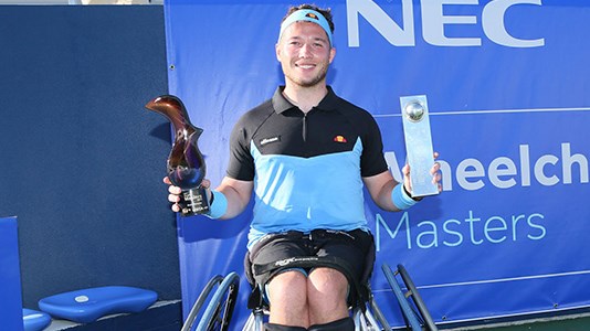 Alfie Hewett smiling in his wheelchair and holding his two awards in both hands