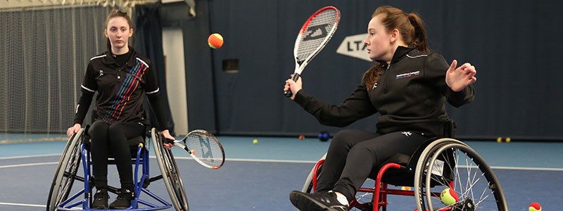 Two women playing wheelchair tennis